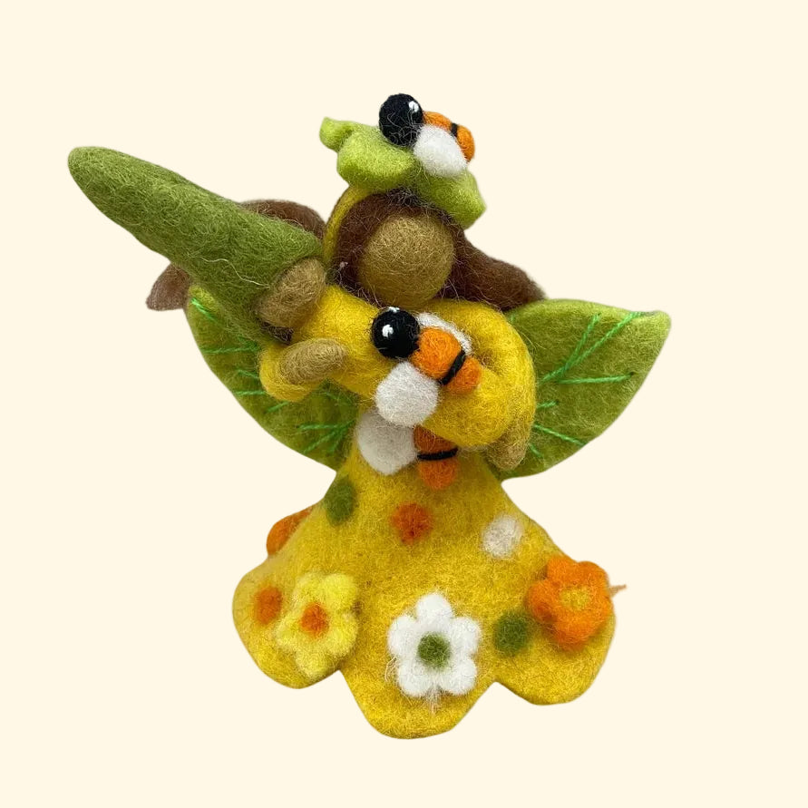 A small felted wool fairy figurine with a yellow dress, green wings, and a brown body, decorated with flowers, shown on a plain white background.