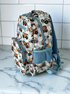 side view of Mini & Mum kids backpack with insulated interior for daycare and outings. can be personalised with childs name. this print is digger dreaming. blue or sage checkers with digger construction trucks vehicles over it