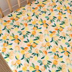 Sunny Citrus organic cotton fitted cot sheet laid flat showing fresh lemon and citrus fruit pattern on soft breathable jersey fabric
