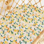 Close up of Sunny Citrus organic cotton bassinet sheet showing detailed lemon and citrus fruit print on breathable jersey fabric
