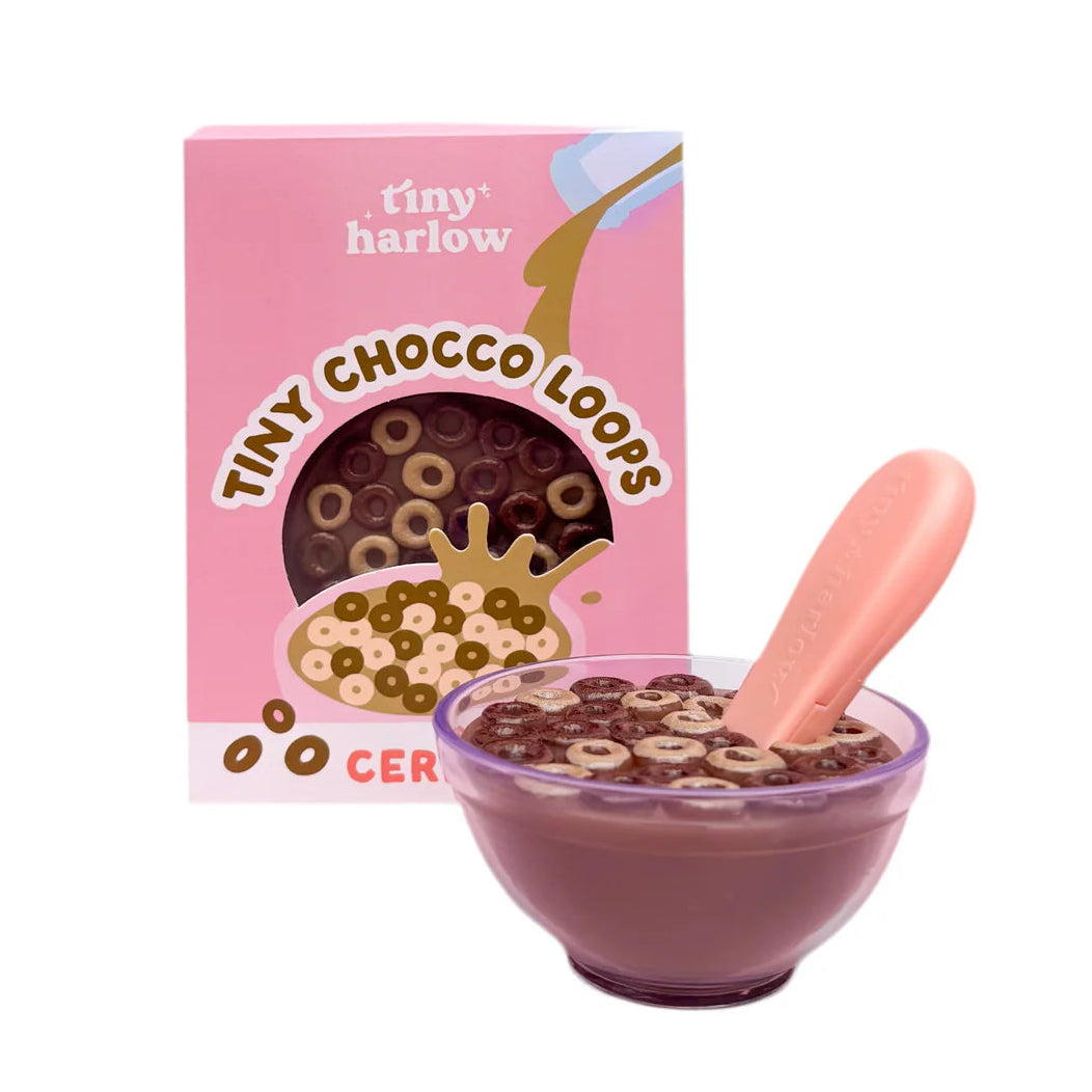 Tiny Tummies Tiny Chocco Loops doll cereal bowl with pretend chocolate loops and pink spoon in front of cereal box packaging for imaginative role play.