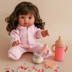 lifestyle photo shoot with mini coletto doll and the my tiny birthday set gift pack which includes a sippy cup of strawberry milk, magic doll food jar and spoon in the flavour birthday cake. the doll is also wearing a suit perfect for gifting and made by tiny harlow