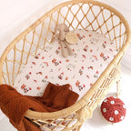 Gnomes organic bassinet sheet fitted on a woven bassinet in a cosy nursery setting with soft neutral bedding