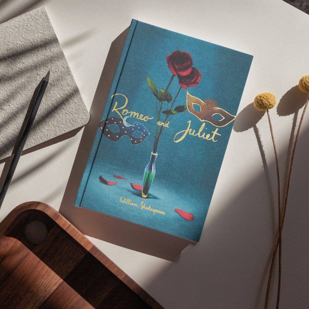 photoshoot of cover Romeo and Juliet collector’s edition hardcover book by William Shakespeare with blue cover, gold foil title, rose illustration and decorative mask
