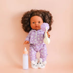 showcased on a mini coletto doll the tiny tummies sleepytime pack gift set out of packaging, includes lilac daisy printed pyjamas for your doll, doll slippers, magic milk and play rattle for your doll and pretend play. brand is tiny harlow