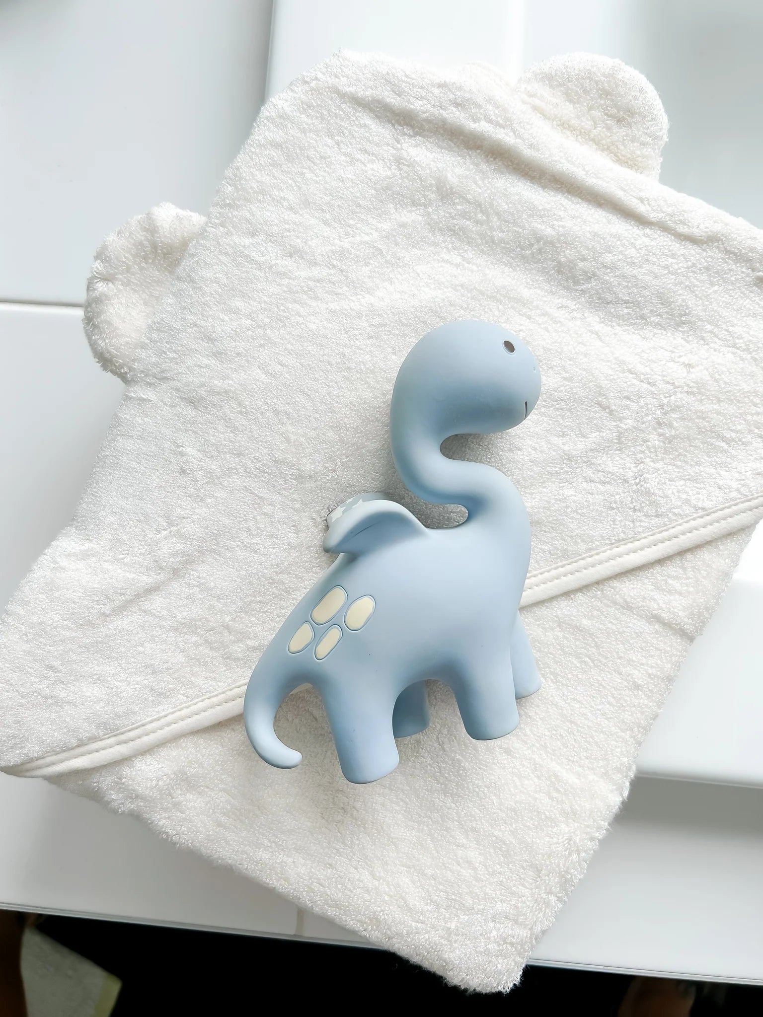 Soft sage baby teething toy by Winnie Parkes with dinosaur design