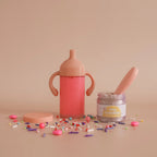 closer look at the my tiny birthday set gift pack which includes a sippy cup of strawberry milk, magic doll food jar and spoon in the flavour birthday cake. made by tiny harlow