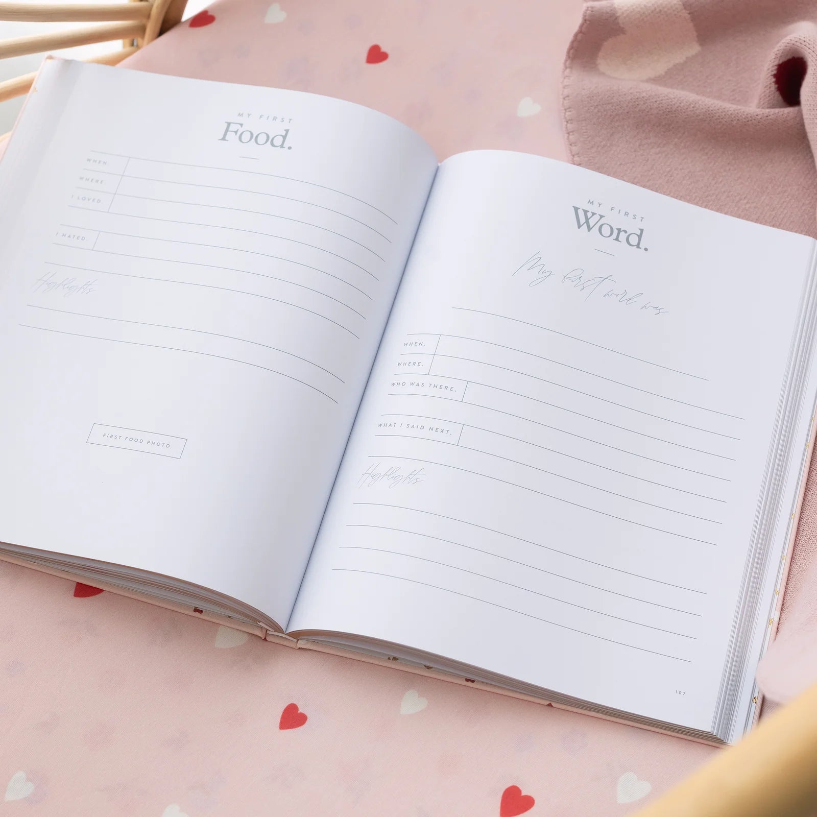 Open notebook with lined pages on a pink surface with heart patterns