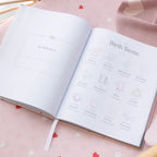 Open book with 'Birth Stone' page on a pink surface with heart patterns
