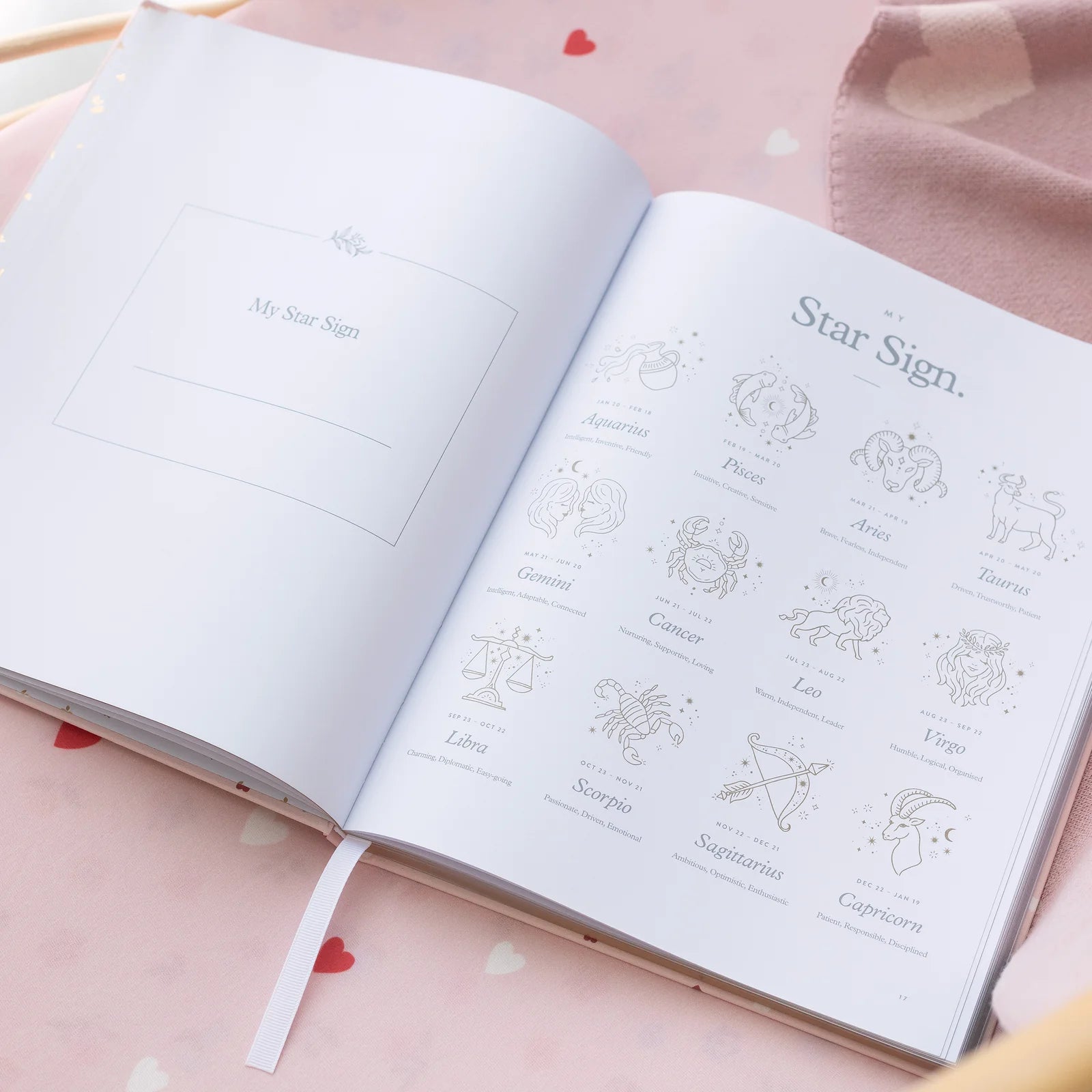 Open book with star sign illustrations on a pink surface