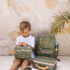kid sitting with Fox & Fallow backpack for kids, perfect for school, daycare and everyday use. Spacious, practical and designed for little adventures. Personalisation of embroidery with name also available on bags in 2 placements. This print is dinos and has matching lunch bags