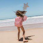 on beach shoot of Fox & Fallow backpack for kids, perfect for school, daycare and everyday use. Spacious, practical and designed for little adventures. Personalisation of embroidery with name also available on bags in 2 placements. This print is dusty roses