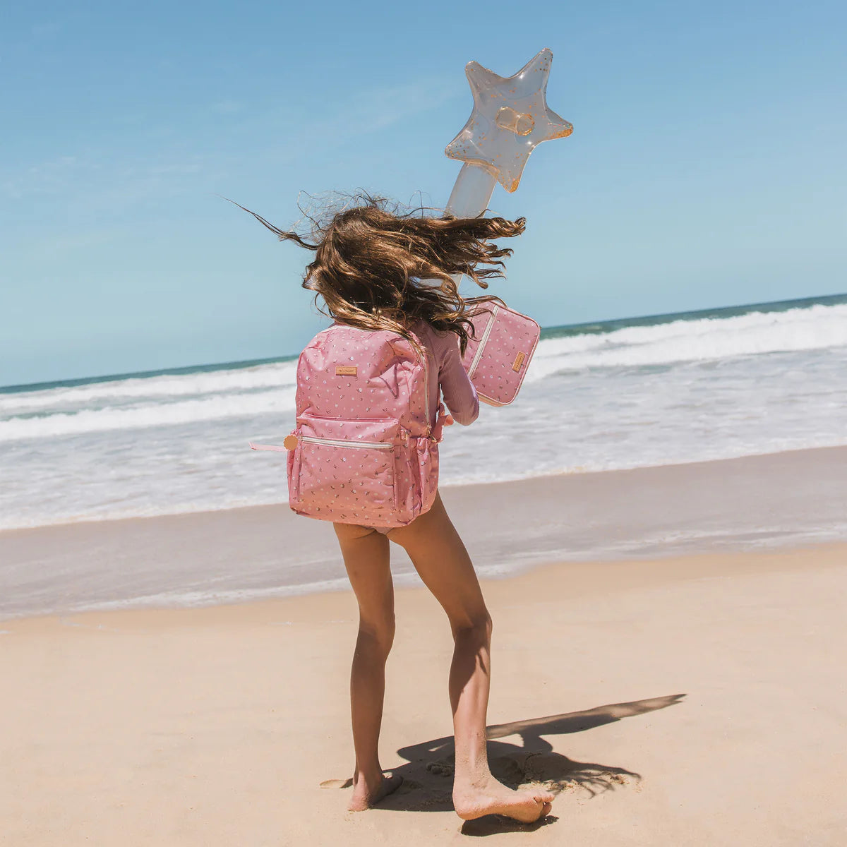 on beach shoot of Fox & Fallow backpack for kids, perfect for school, daycare and everyday use. Spacious, practical and designed for little adventures. Personalisation of embroidery with name also available on bags in 2 placements. This print is dusty roses
