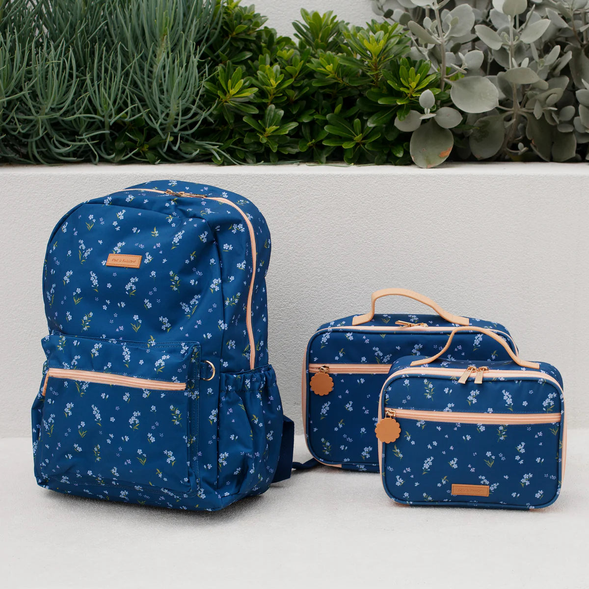 photoshoot of navy bag with florals Fox & Fallow backpack for kids, perfect for school, daycare and everyday use. Spacious, practical and designed for little adventures. Personalisation of embroidery with name also available on bags in 2 placements. This print is forget me not