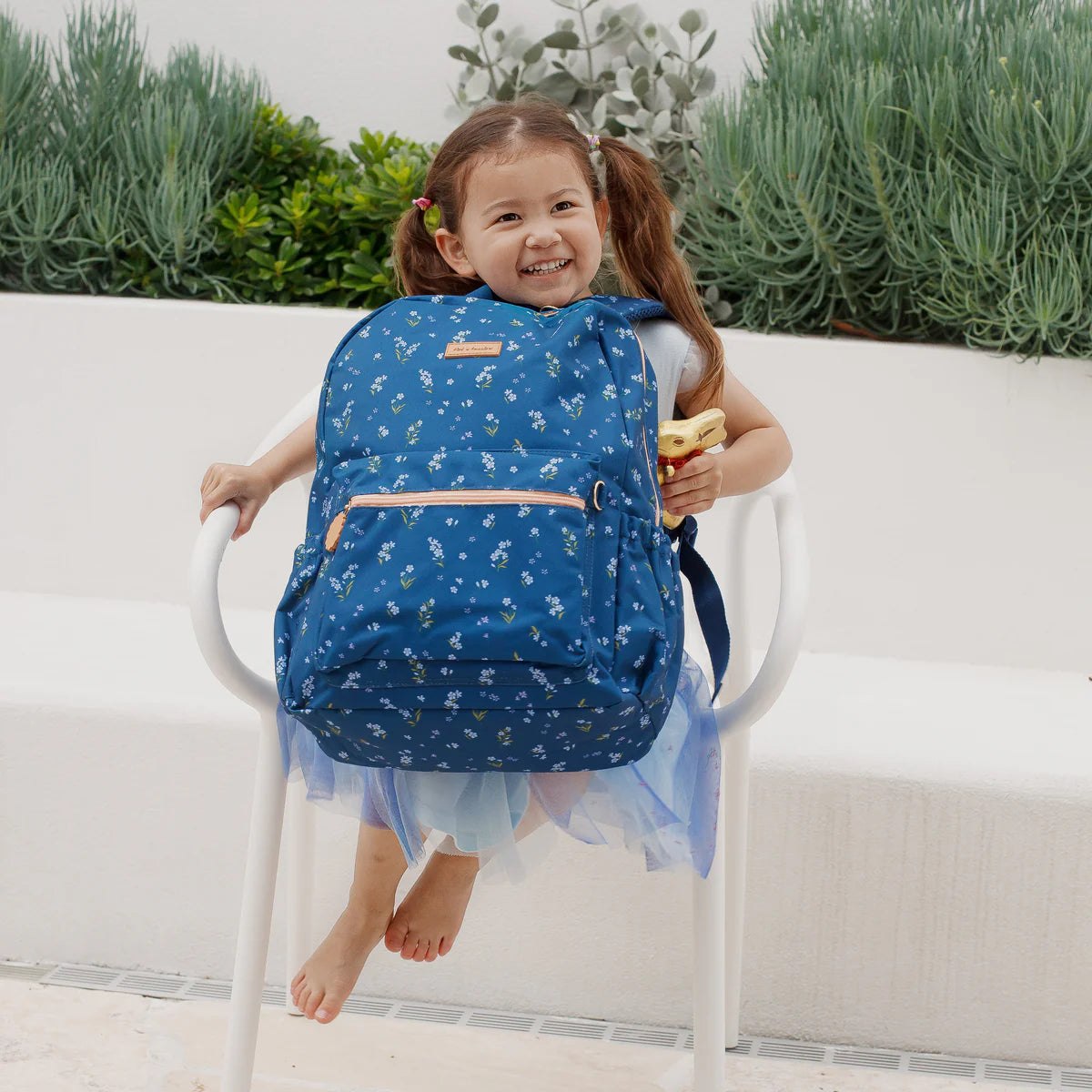 child wearing on front Fox & Fallow backpack for kids, perfect for school, daycare and everyday use. Spacious, practical and designed for little adventures. Personalisation of embroidery with name also available on bags in 2 placements. This print is forget me not