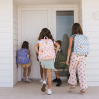 kids walking in home wearing Fox & Fallow backpack for kids, perfect for school, daycare and everyday use. Spacious, practical and designed for little adventures. Personalisation of embroidery with name also available on bags in 2 placements. This print is daisy chain, sage check, juniper and dinosaur