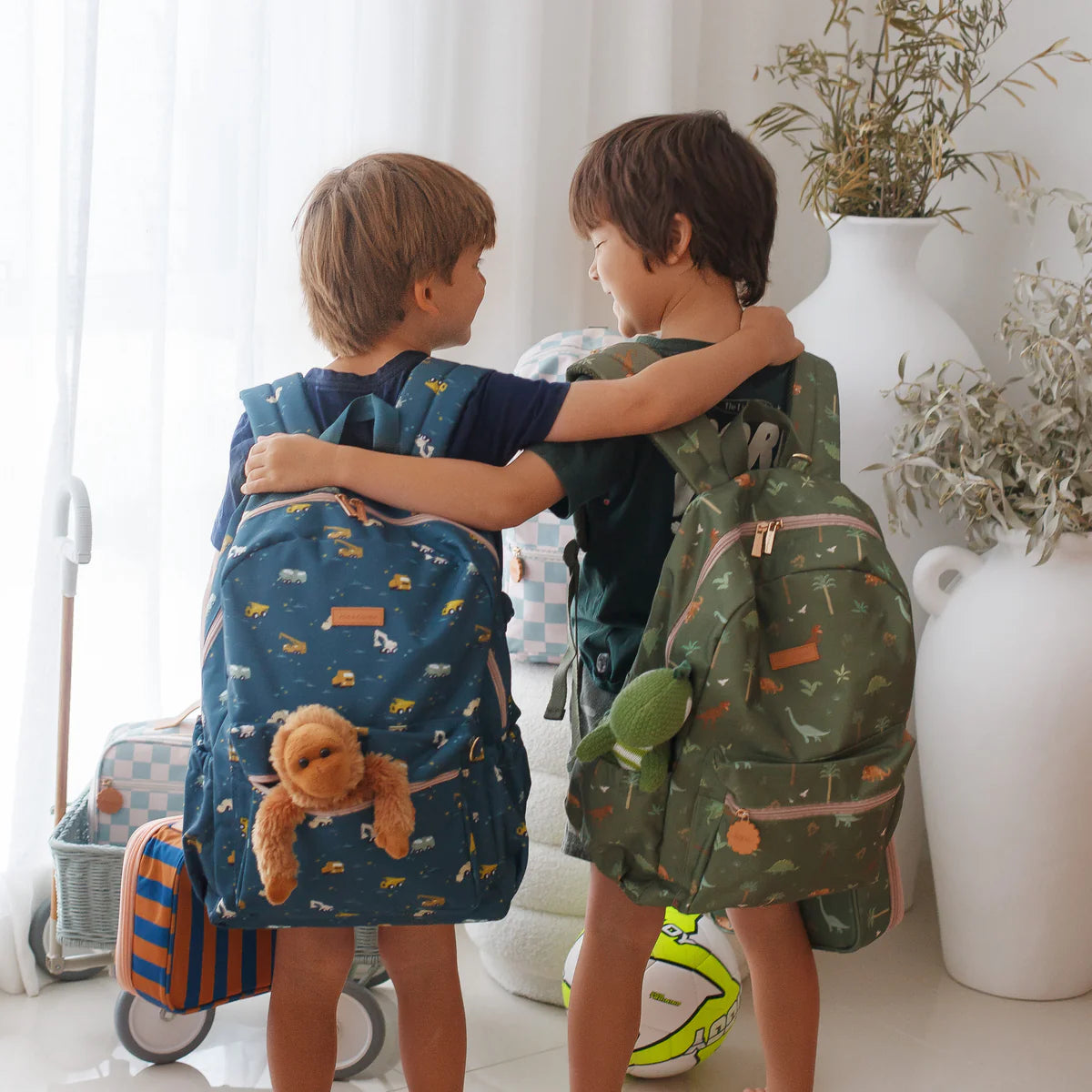 children friends wearing Fox & Fallow backpack for kids, perfect for school, daycare and everyday use. Spacious, practical and designed for little adventures. Personalisation of embroidery with name also available on bags in 2 placements. This print is dinos and trucks