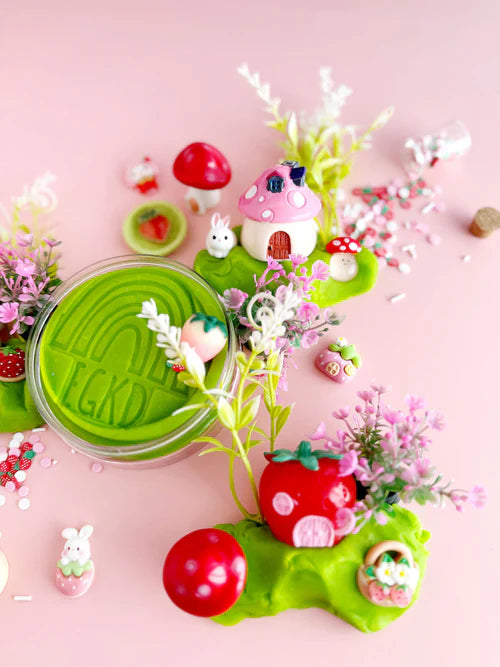 Top view of green sensory play dough with strawberry and berry themed mix-ins, bunny village accessories and fine motor sensory pieces
