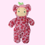 A plush doll dressed in a pink spotted onesie with a hood, green leaf on the head, and a pale beige face, centered on a plain white background.