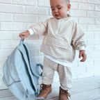 child holding Corduroy kids backpack with front pocket, laptop sleeve, health label, name label, options to personalise a name with embroidery, spacious. perfect for school or travel. this colour is powder blue
