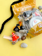 Kids construction sensory play kit with textured grey playdough, construction vehicle, shovel, rocks and small world building accessories.