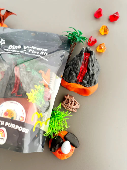 Dino themed playdough sensory kit with volcano, prehistoric plants, lava rocks and dinosaur toys arranged for tactile and imaginative kids play