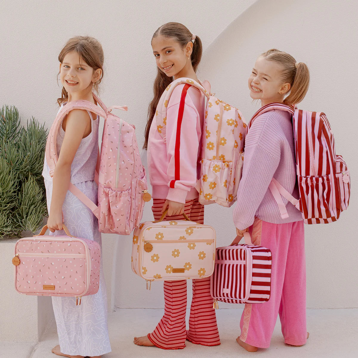 friends photoshoot of modelling the Fox & Fallow backpack for kids, perfect for school, daycare and everyday use. Spacious, practical and designed for little adventures. Personalisation of embroidery with name also available on bags in 2 placements. This print is dusty roses, daisy chains and burgundy stripes. all have matching lunch bags