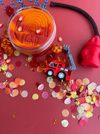 Close-up of red sensory playdough with colourful beads and themed accessories for tactile fine motor play