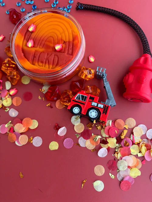 Close-up of red sensory playdough with colourful beads and themed accessories for tactile fine motor play