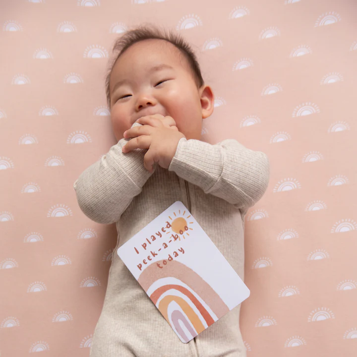 photoshoot of baby with milestone cards by lively living to track babies age and milestones. great for photos and theme is bohemian bliss. card pictured reads i played peek a boo today