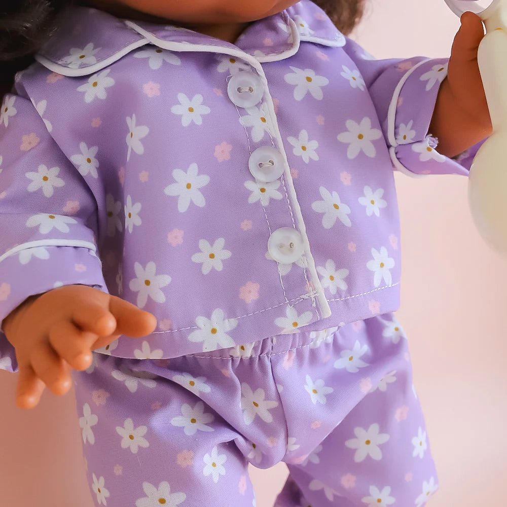 close up of the fabric of the tiny tummies sleepytime pack gift set out of packaging, includes lilac daisy printed pyjamas for your doll, doll slippers, magic milk and play rattle for your doll and pretend play. brand is tiny harlow