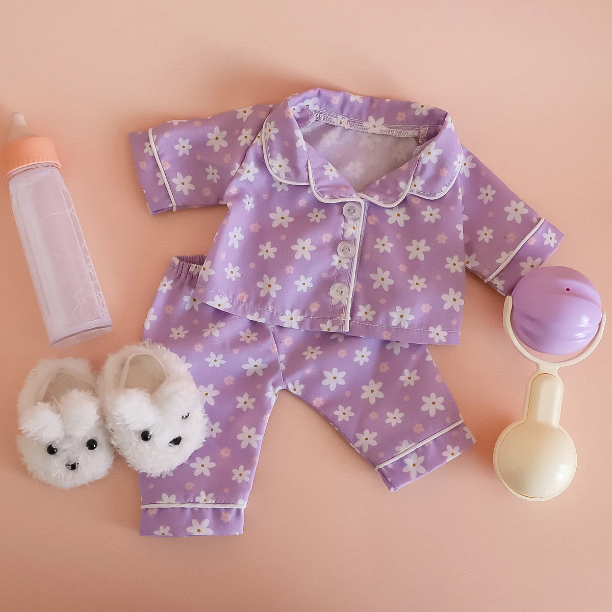 showcasing the tiny tummies sleepytime pack gift set out of packaging, includes lilac daisy printed pyjamas for your doll, doll slippers, magic milk and play rattle for your doll and pretend play. brand is tiny harlow