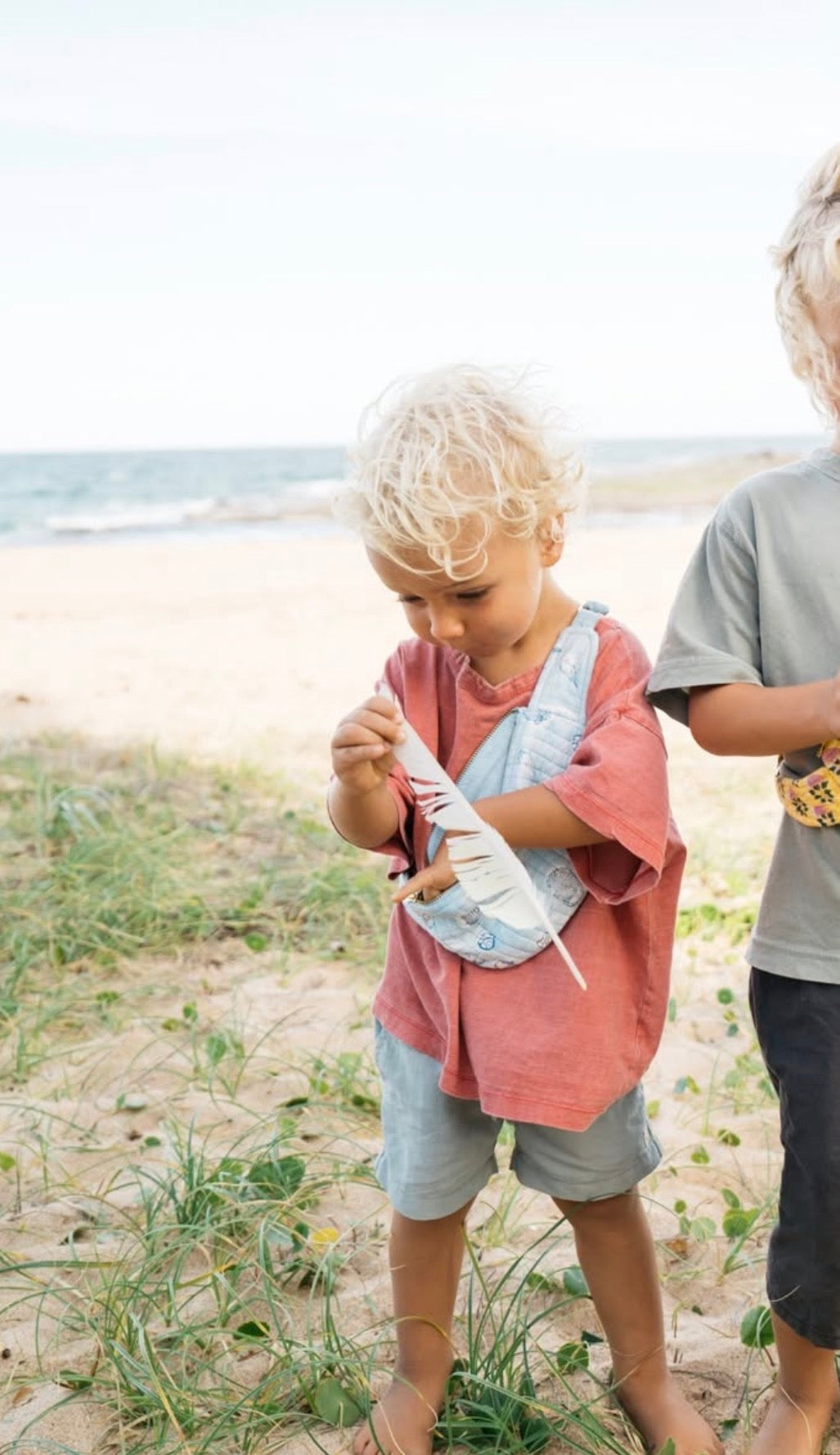 kid wearing crossbody bag and collecting feathers picnic folk