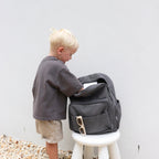 kid digging inside his Corduroy kids backpack with front pocket, laptop sleeve, health label, name label, options to personalise a name with embroidery, spacious. perfect for school or travel. this colour is charcoal
