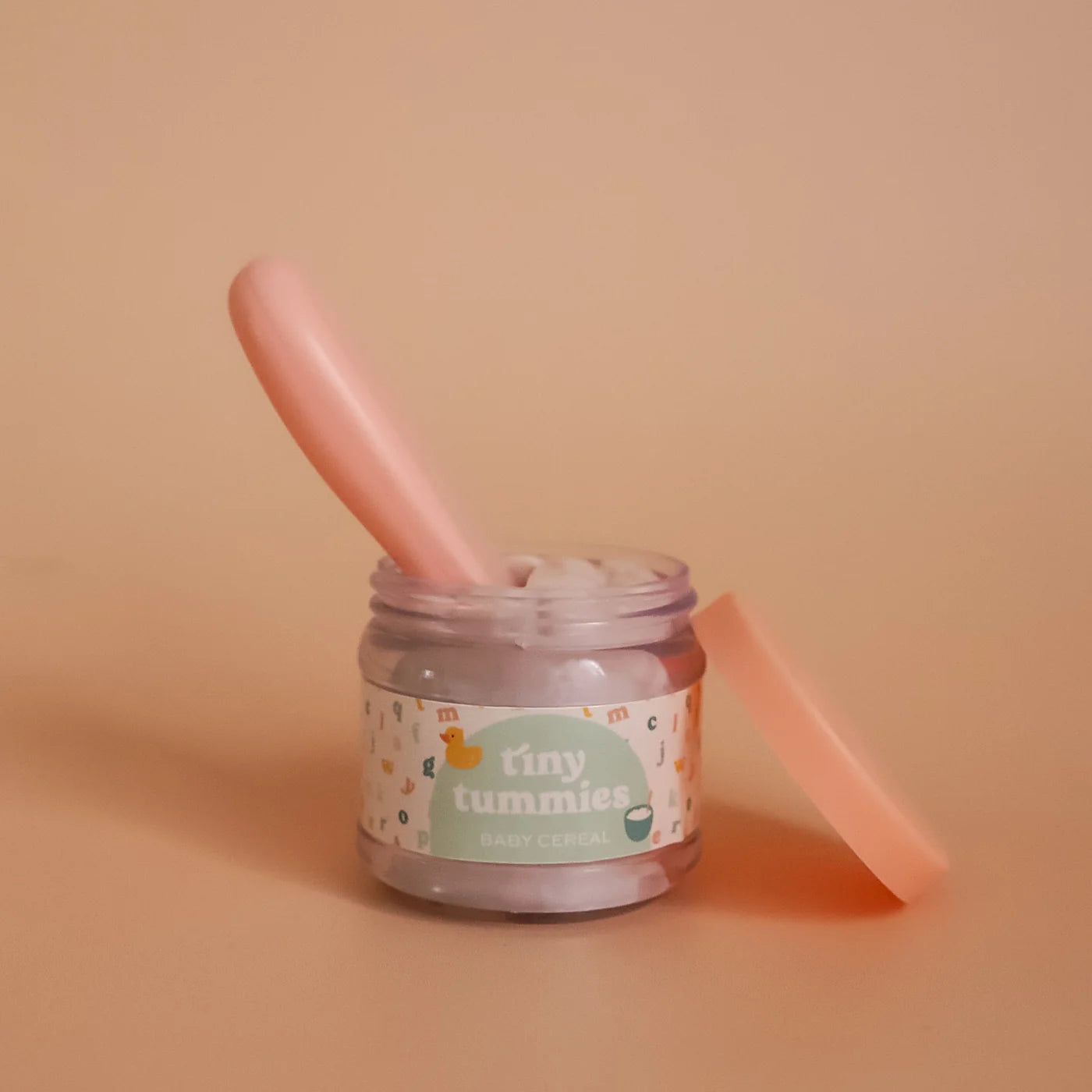 a closer look at just the tiny tummies jar of baby cereal with it's magic spoon. brand is tiny harlow 