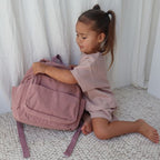child holding Corduroy kids backpack with front pocket, laptop sleeve, health label, name label, options to personalise a name with embroidery, spacious. perfect for school or travel. this colour is dusty rose