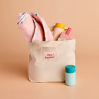 closer look of the tiny harlow bath accessory pack that comes with a bag, body lotion,baby doll towel, baby powder and bubble bath all for pretend play with dolls called tiny bath time