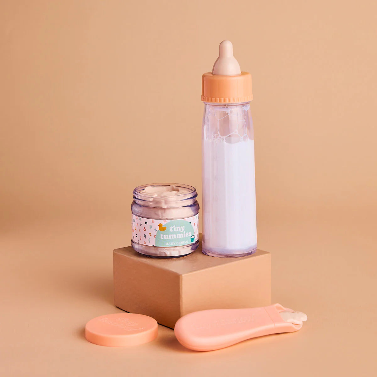 a closer look of the my first tiny tummies gift pack out of the box which includes a milk bottle that disappears, and the tiny tummies jar of baby cereal with it's magic spoon. brand is tiny harlow 