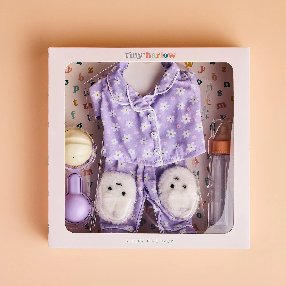shown in packaging great for gifting the tiny tummies sleepytime pack gift set includes lilac daisy printed pyjamas for your doll, doll slippers, magic milk and play rattle for your doll and pretend play. brand is tiny harlow