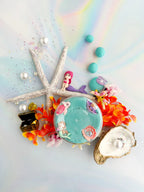 Under the sea playdough set with textured blue dough, starfish, shells, coral reef pieces and mermaid toys arranged for small world sensory play