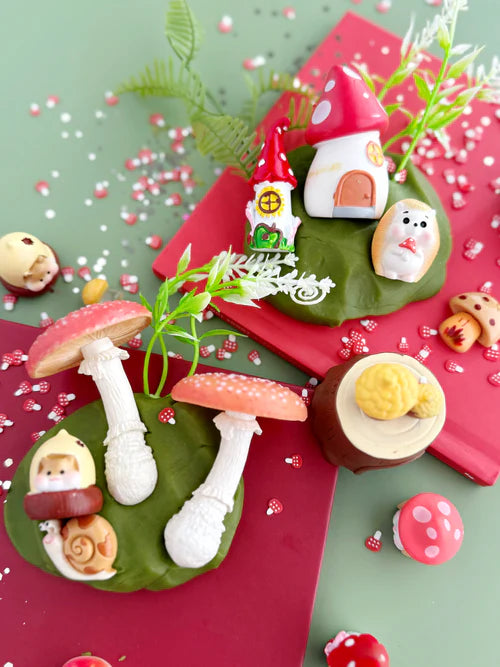 Kids forest sensory play kit with mushrooms, hedgehog toy, miniature houses and nature themed accessories arranged around resealable KidDough pouch