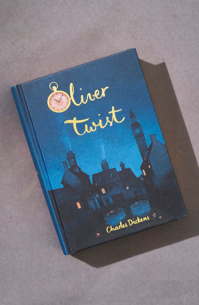  Oliver Twist collector’s edition hardcover by Charles Dickens with navy blue illustrated cover, gold foil title, cloth-bound finish.