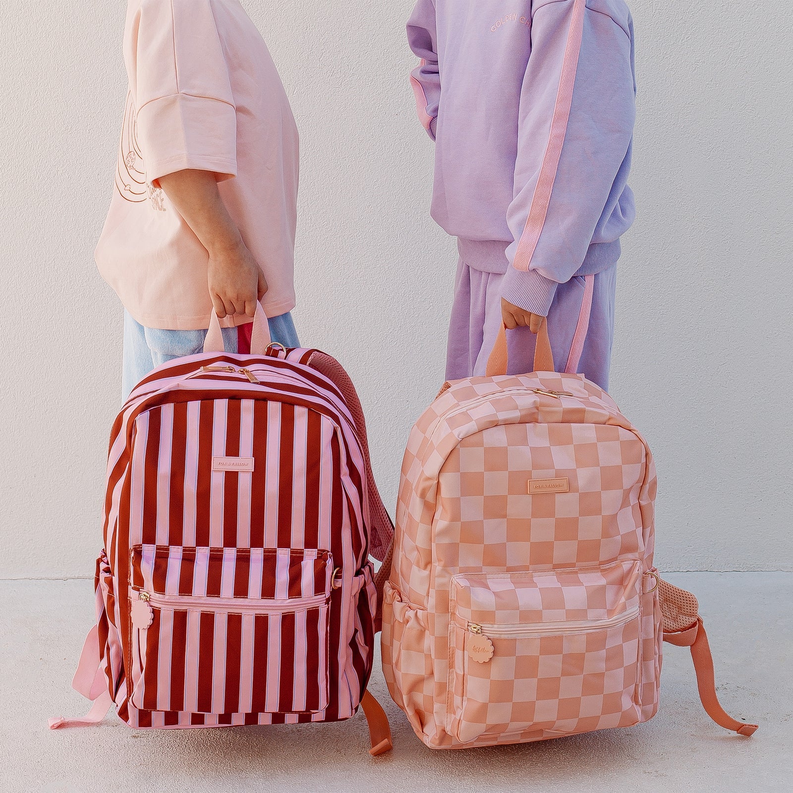 photoshoot of Fox & Fallow backpack for kids, perfect for school, daycare and everyday use. Spacious, practical and designed for little adventures. Personalisation of embroidery with name also available on bags in 2 placements. This print is peach checks and burgundy stripe