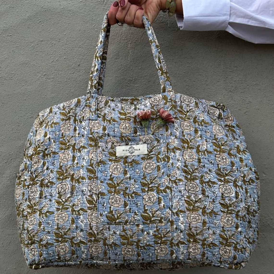 quilted duffle style bag with floral pattern and strap