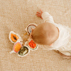 baby holding soft fruit toy with crinkle and rattle sensory play