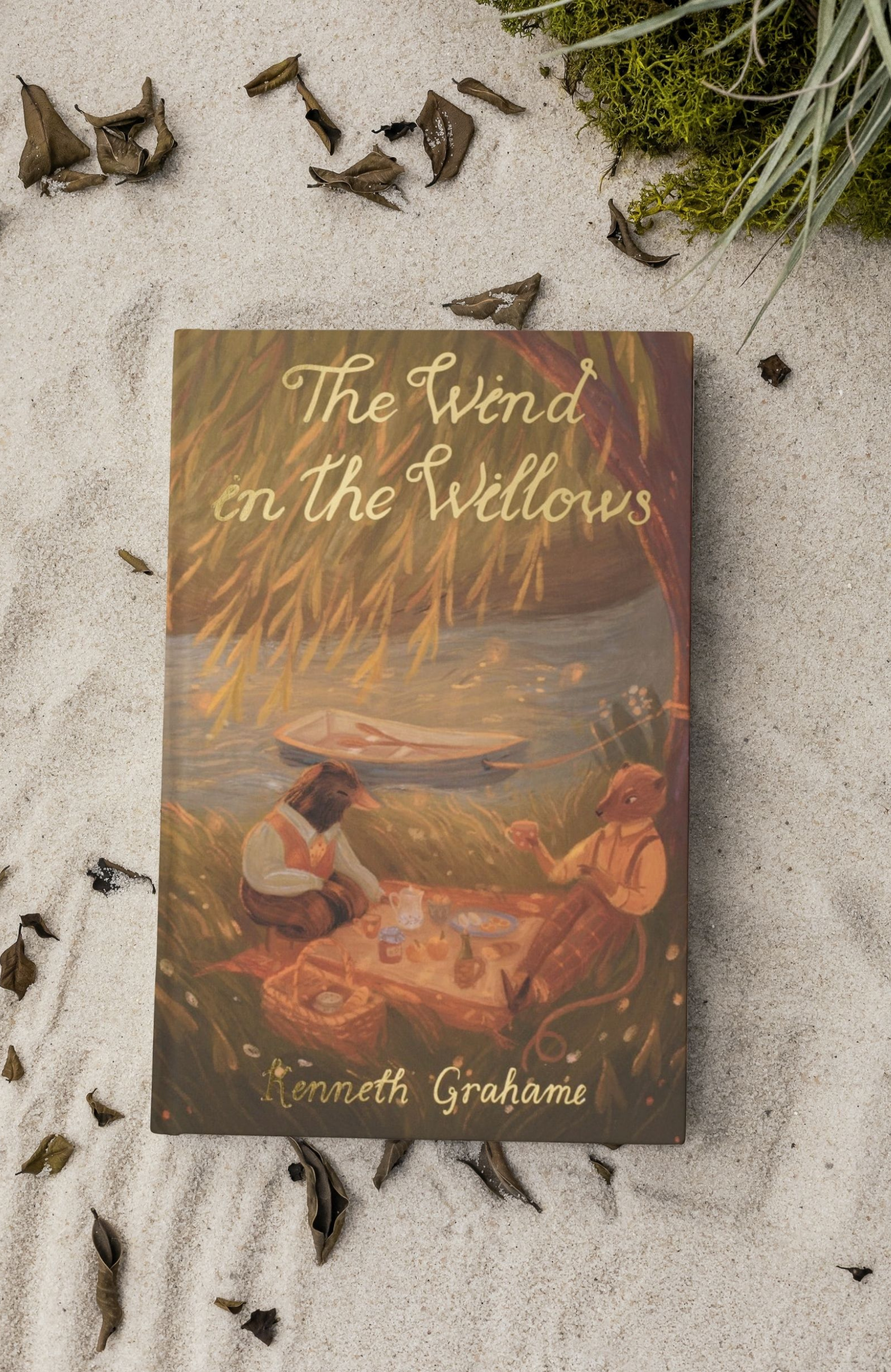 The Wind in the Willows paperback book by Kenneth Grahame with illustrated cover showing woodland animals having a picnic by the river