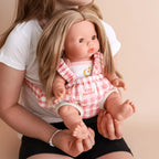 kid wearing the baby dolls carrier made by tiny harlow with baby inside. good for pretend play, the print is pink gingham