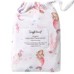 Snuggle Hunny Mermaid organic bassinet sheet folded inside matching drawstring bag with soft pastel mermaid print