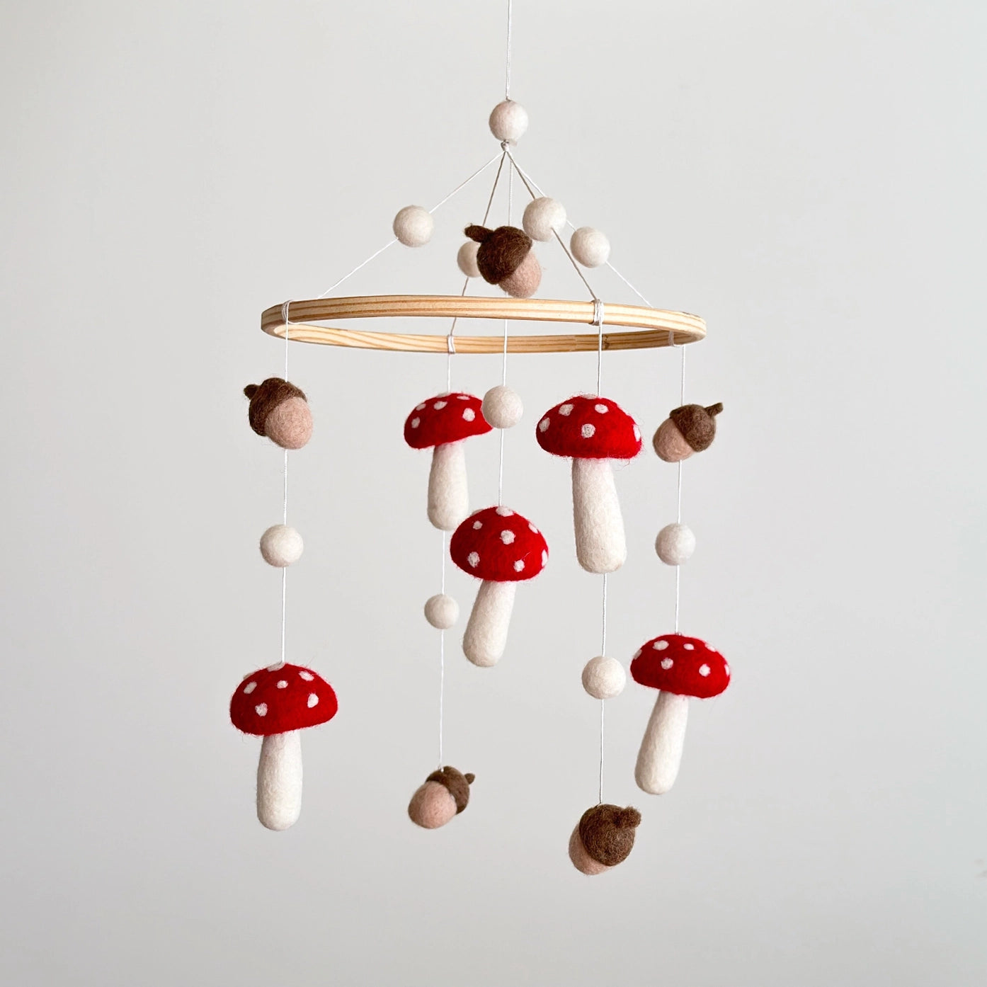 Handmade woodland nursery baby mobile with felt toadstools, acorns and wooden hanging frame