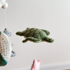 Children's mobile with hanging plush toys including a turtle, whale, and fish against a light background
